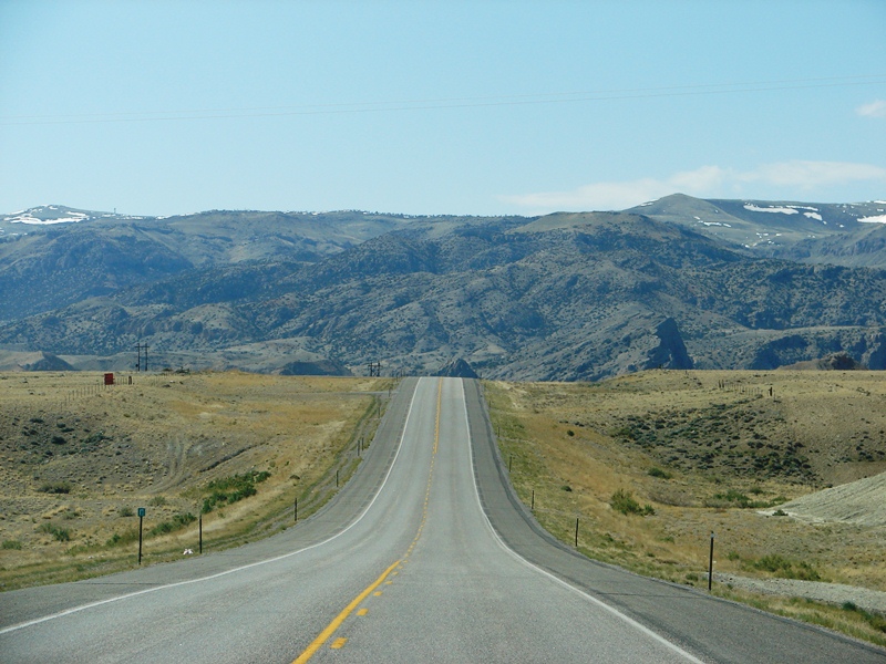 The Owl Creek Mountains at Wind River Canyon rise beyond the rise in the road.
